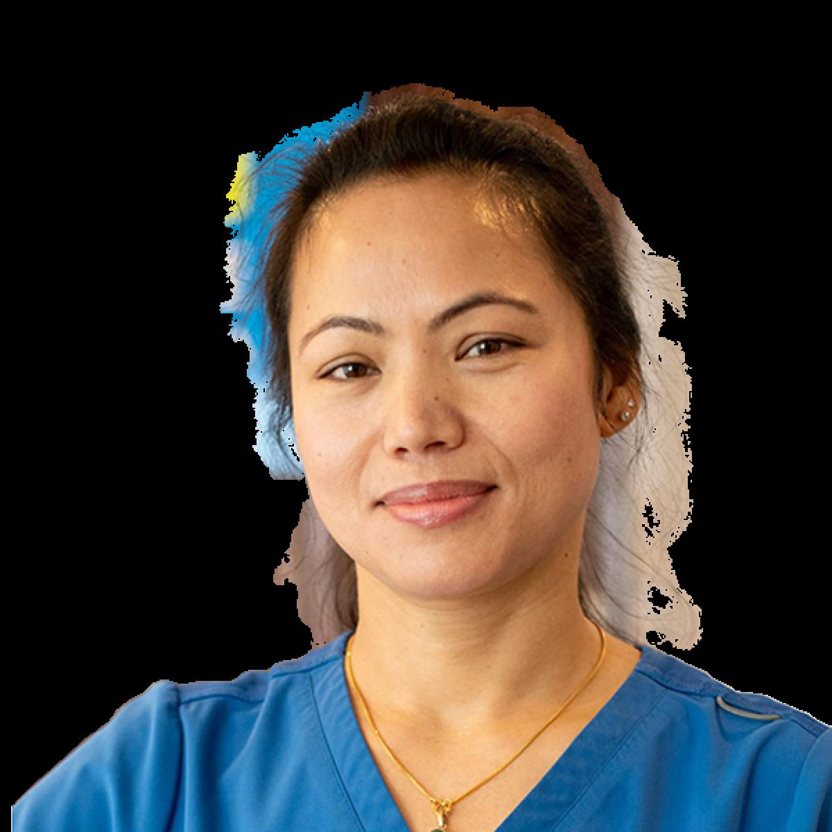 Female healthcare professional wearing blue medical scrubs, smiling at camera for professional headshot