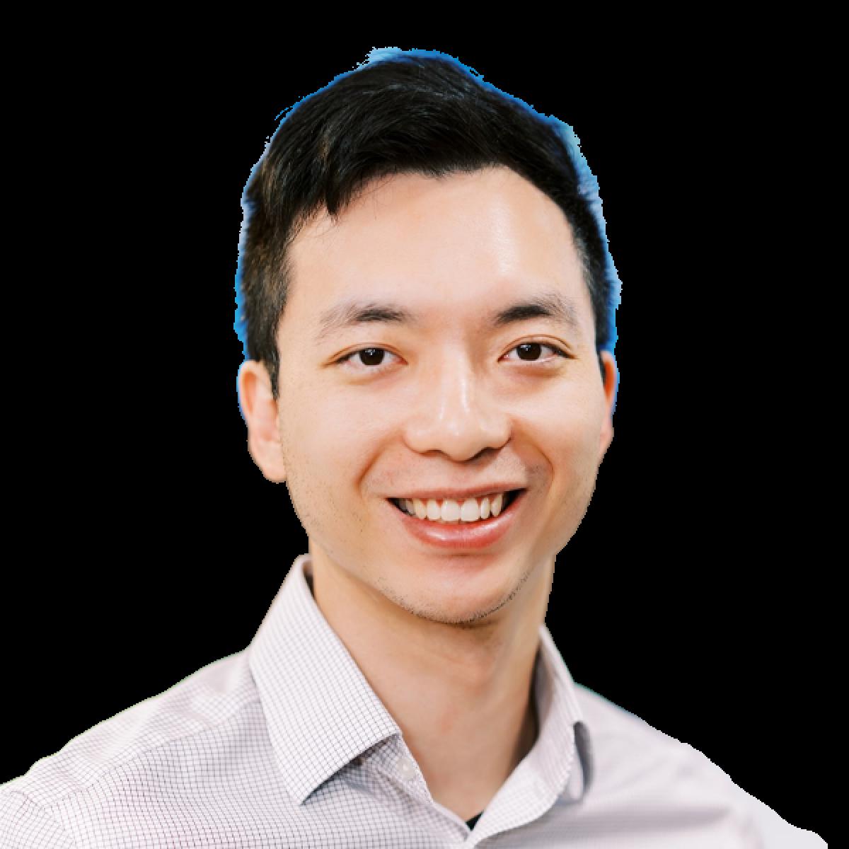Professional headshot of smiling Asian male doctor in light grey checkered shirt against white background